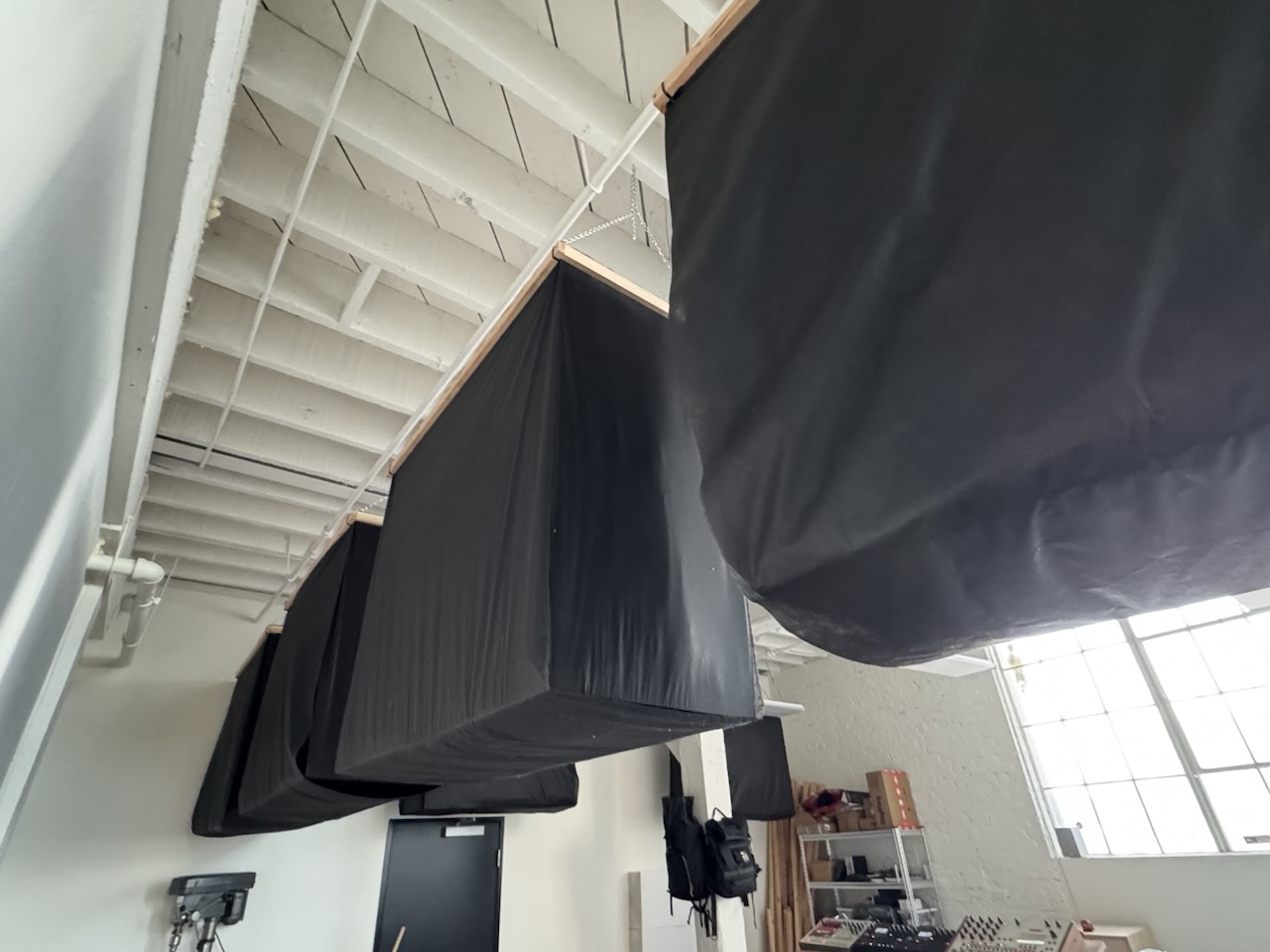Black fabric-wrapped absorbers hanging high off the studio walls under the roof trusses.