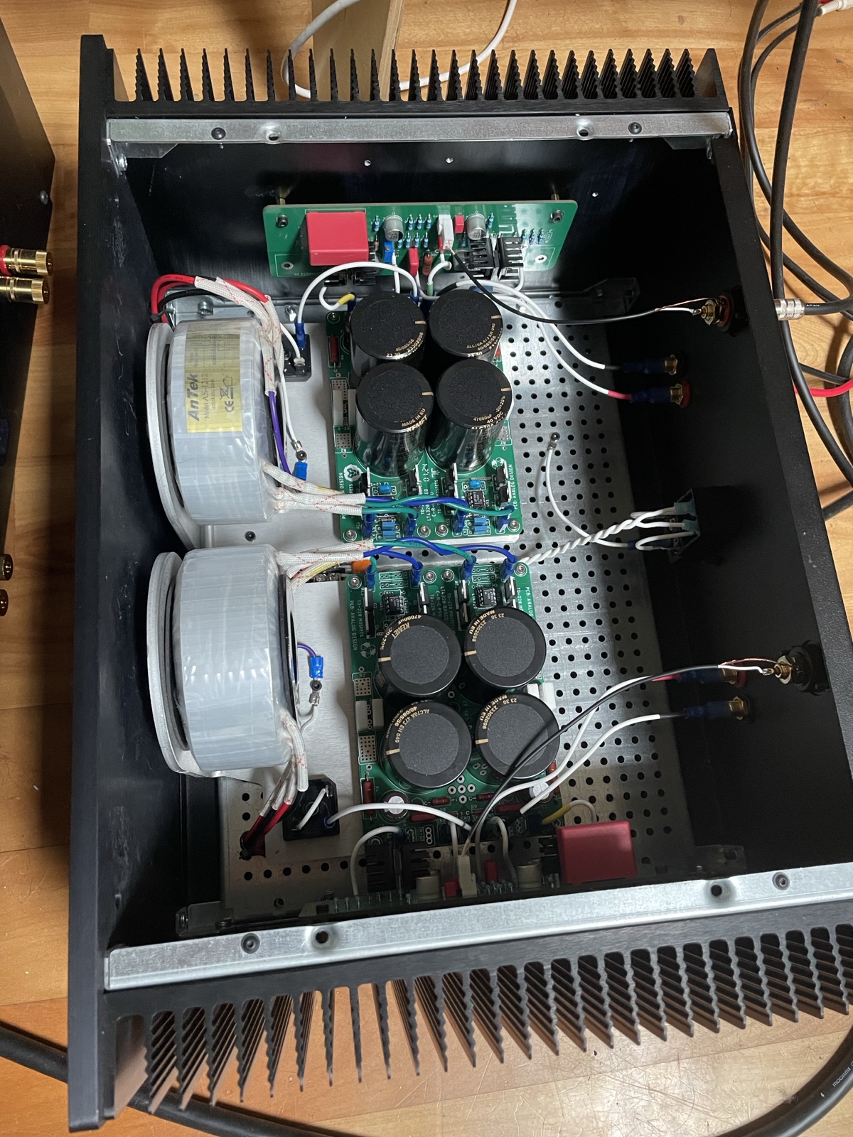 Inside the amplifier from above: two toroidal transformers on the left, two amplifier boards each with four large capacitors, between finned heatsinks.